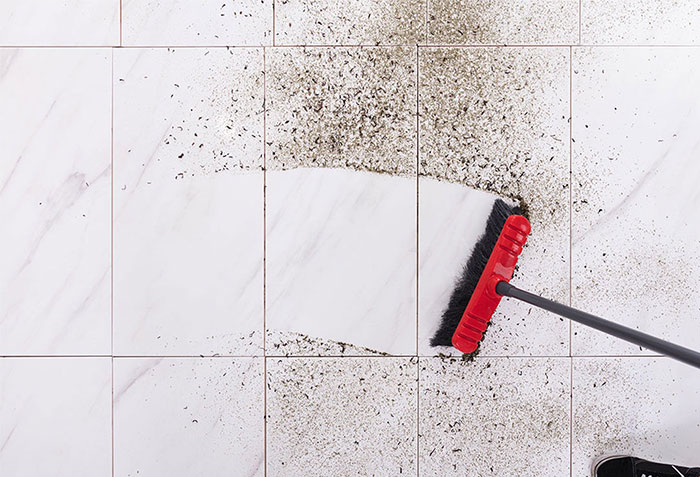 Broom sweeping away dirt on a tile floor | California Renovation