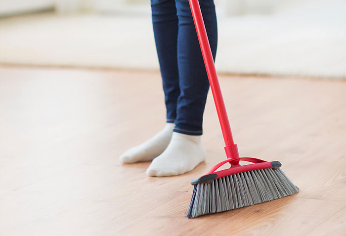 Broom sweeping across laminate flooring | California Renovation